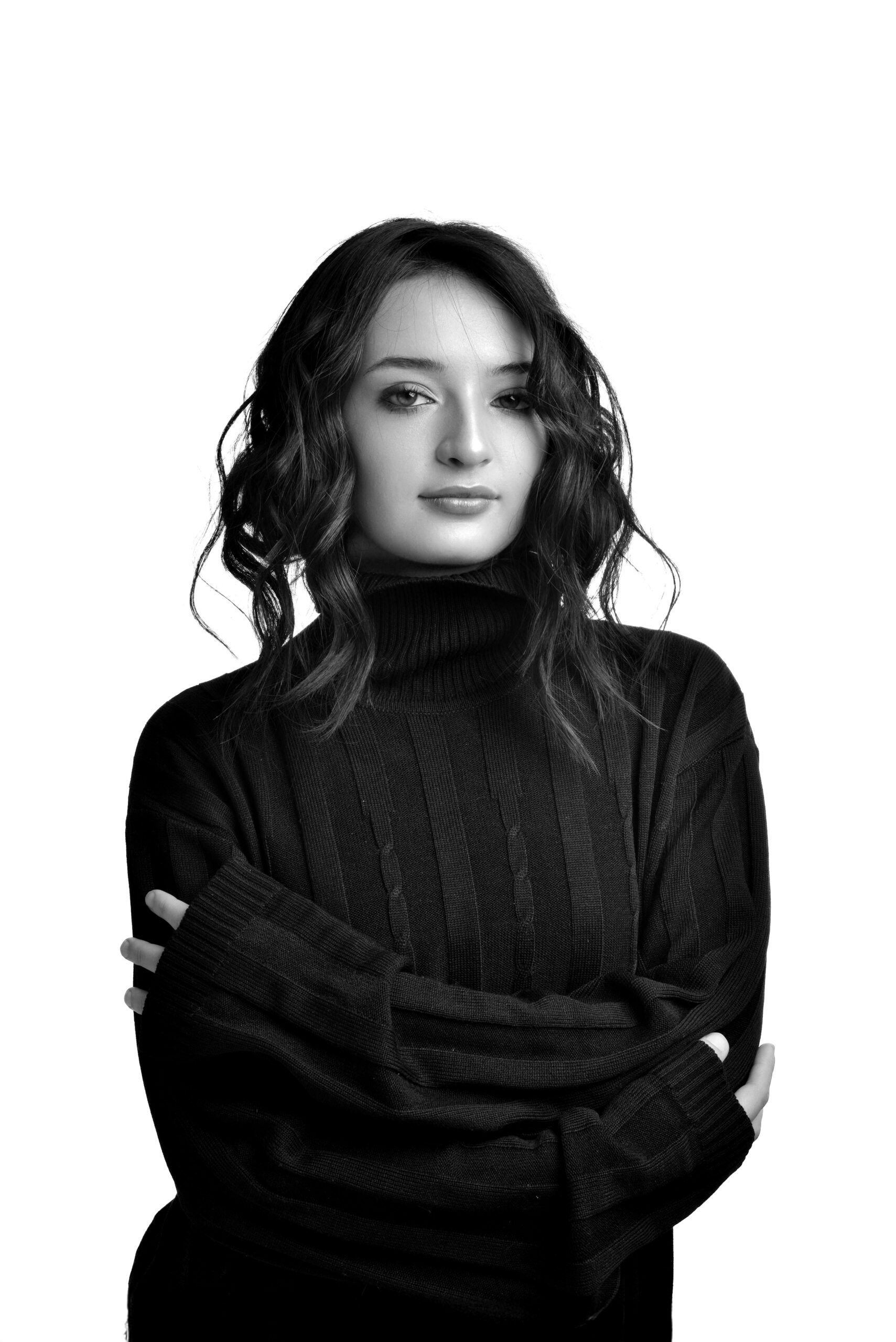 Elegant black and white portrait of a young woman in a sweater against a white backdrop.